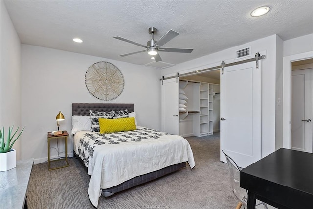 bedroom with ceiling fan, a barn door, and a textured ceiling