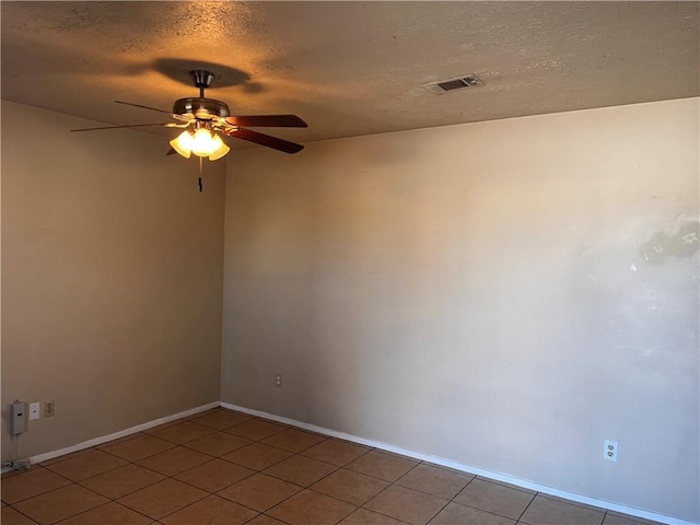 empty room with ceiling fan, a textured ceiling, and light tile patterned floors