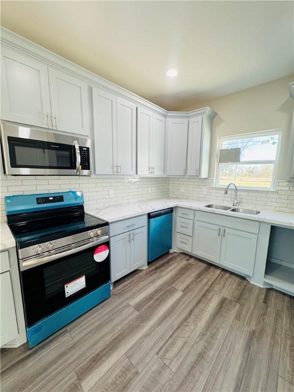 kitchen with sink, decorative backsplash, stainless steel appliances, and white cabinets