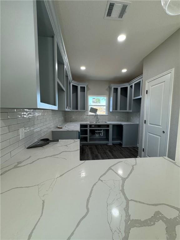 kitchen with light stone countertops, sink, backsplash, and dark hardwood / wood-style flooring