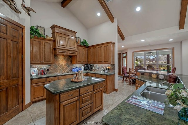 kitchen featuring beamed ceiling, light tile patterned floors, tasteful backsplash, and a kitchen island with sink