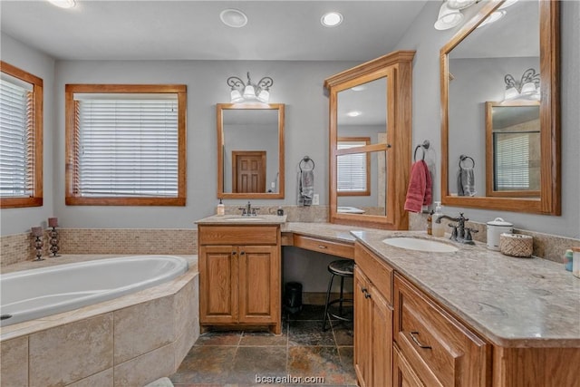 bathroom with vanity, a relaxing tiled tub, and plenty of natural light