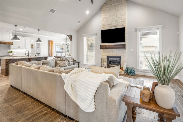 living room featuring high vaulted ceiling, sink, dark hardwood / wood-style floors, and a fireplace