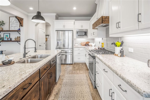 kitchen featuring stainless steel appliances, white cabinets, pendant lighting, ornamental molding, and sink