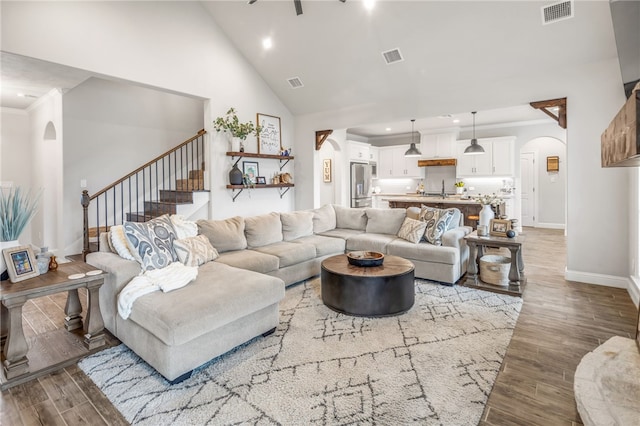 living room featuring ornamental molding, high vaulted ceiling, sink, and wood-type flooring