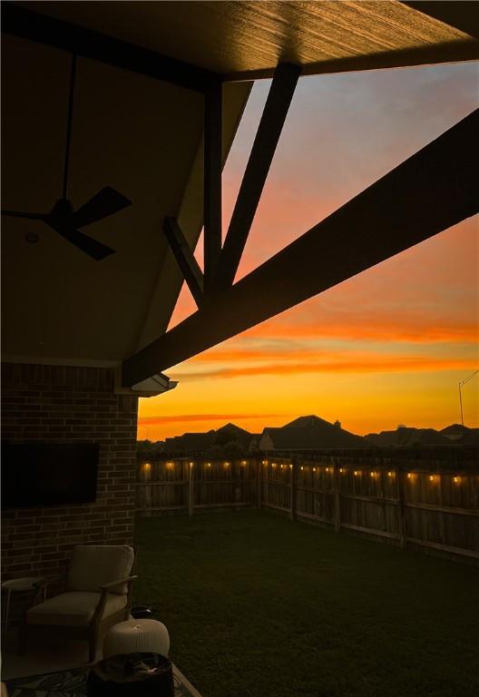 yard at dusk featuring ceiling fan