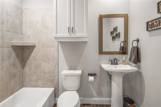 bathroom with toilet, tiled shower / bath, and wood-type flooring