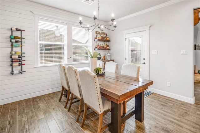 dining room with light hardwood / wood-style floors, a chandelier, and crown molding