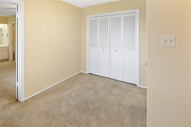 unfurnished bedroom with light colored carpet and a closet