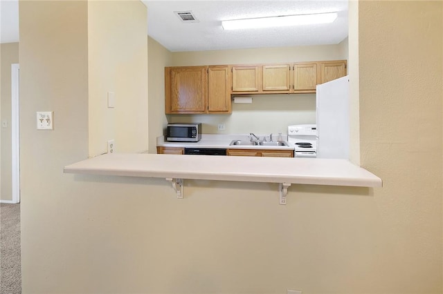 kitchen featuring light brown cabinetry, white appliances, a breakfast bar area, and kitchen peninsula