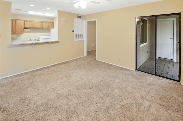 unfurnished living room with sink, light colored carpet, and ceiling fan