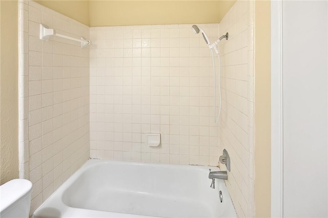 bathroom featuring toilet and tiled shower / bath combo