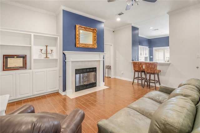 living area featuring baseboards, ornamental molding, ceiling fan, and a tile fireplace