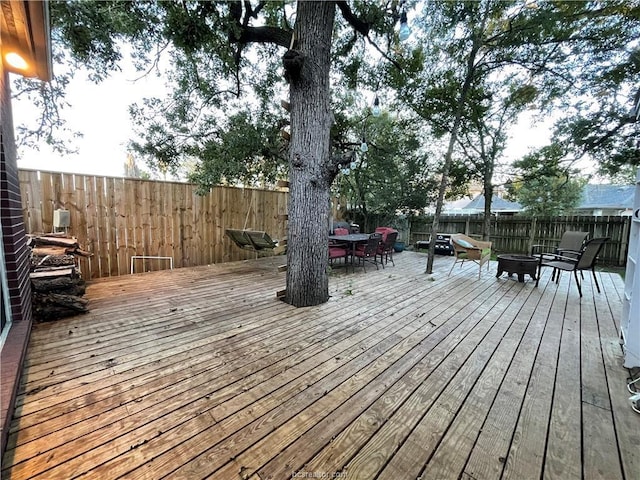 wooden terrace featuring outdoor dining space, an outdoor fire pit, and a fenced backyard