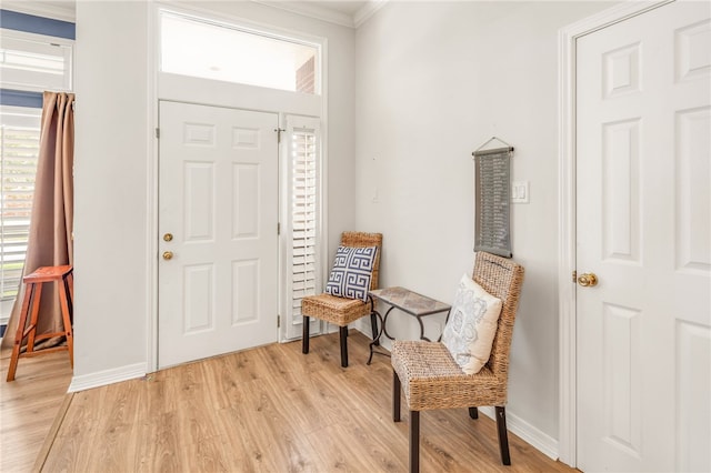 foyer entrance featuring ornamental molding, light wood finished floors, and baseboards