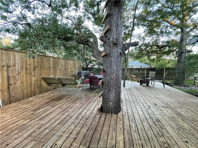 wooden deck with a fire pit and a fenced backyard