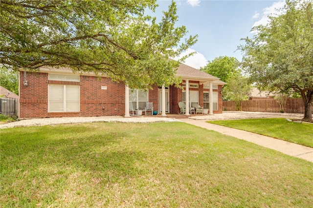 back of property with brick siding, fence, and a yard