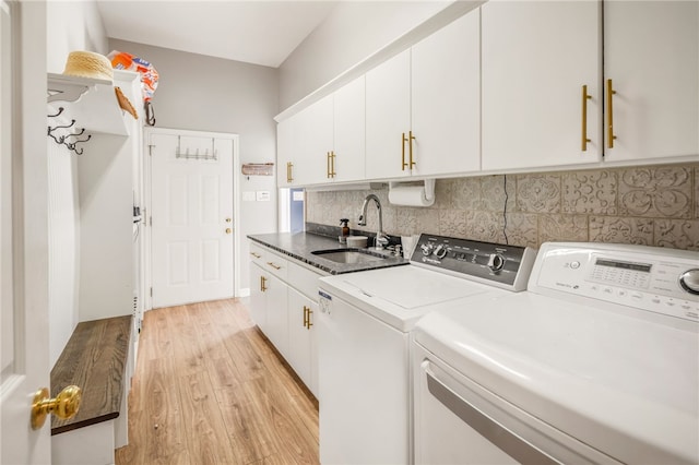 laundry room with cabinet space, separate washer and dryer, light wood finished floors, and a sink