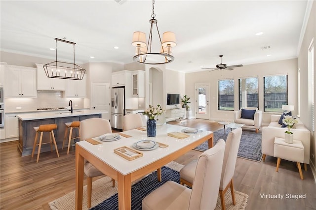 dining room with sink, light hardwood / wood-style floors, and ceiling fan with notable chandelier