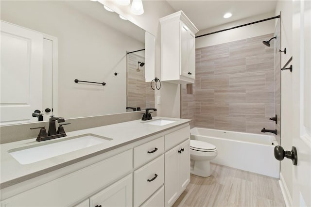 full bathroom featuring tiled shower / bath, vanity, and toilet