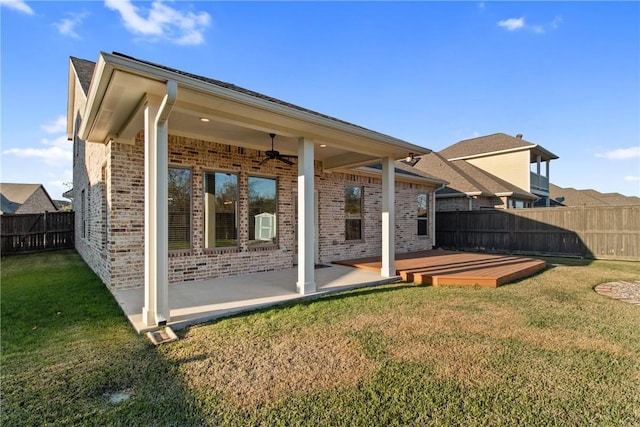 rear view of house featuring ceiling fan, a lawn, and a wooden deck