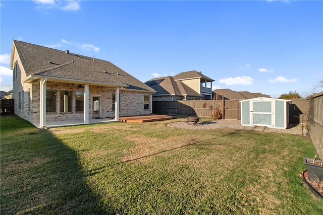 rear view of house featuring a storage shed, a lawn, a patio area, and a wooden deck