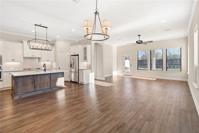 kitchen featuring a center island with sink, ceiling fan with notable chandelier, stainless steel appliances, and hanging light fixtures