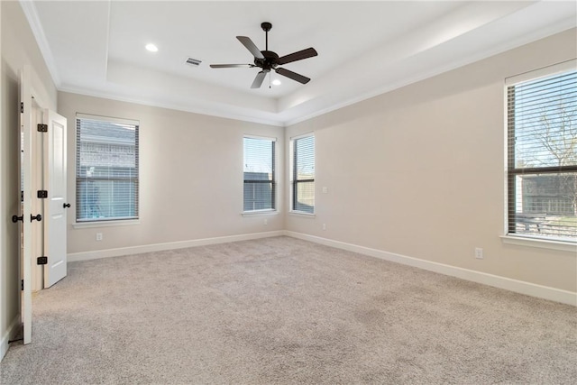 spare room featuring a tray ceiling, ceiling fan, light colored carpet, and ornamental molding