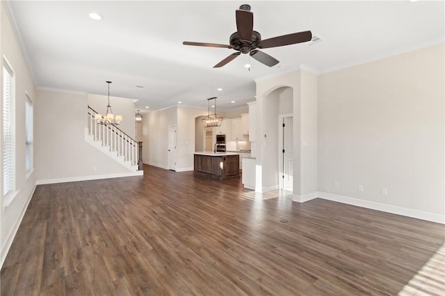 unfurnished living room with ceiling fan with notable chandelier, sink, ornamental molding, and dark wood-type flooring