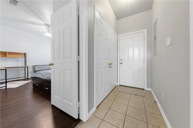 hallway featuring light tile patterned floors, visible vents, and baseboards