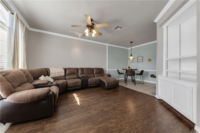 living area with visible vents, wood finished floors, crown molding, baseboards, and ceiling fan