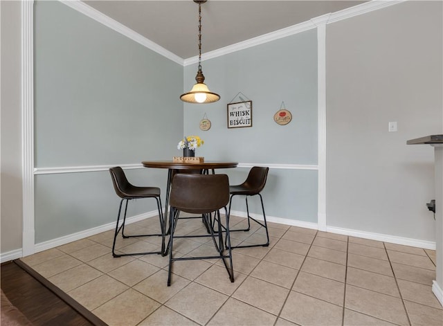 dining space with light tile patterned floors, crown molding, and baseboards