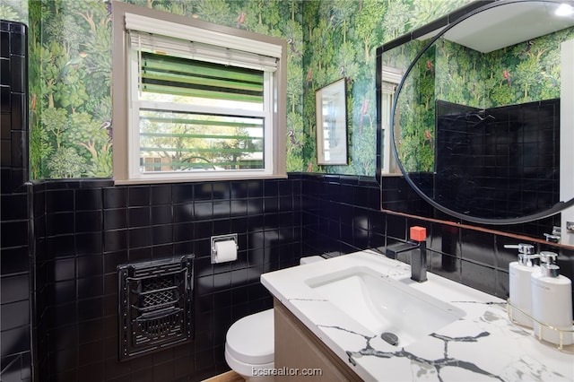 bathroom with vanity, toilet, heating unit, and tile walls