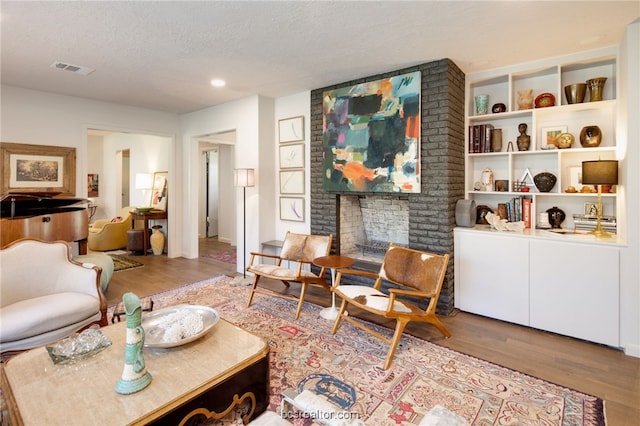 living room with wood-type flooring, a fireplace, and a textured ceiling