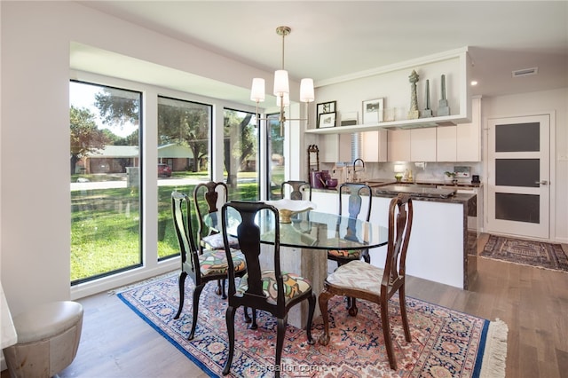 dining space featuring sink, a notable chandelier, and wood-type flooring