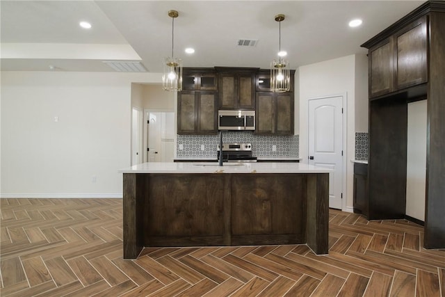 kitchen with appliances with stainless steel finishes, dark brown cabinets, and dark parquet floors