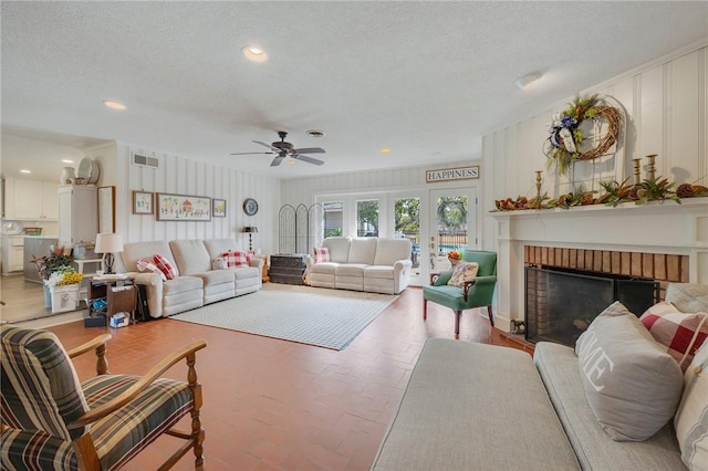 living room featuring ceiling fan, a fireplace, and a textured ceiling