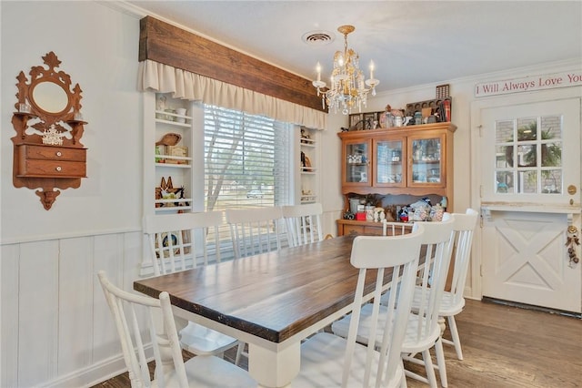 dining area with crown molding, wood-type flooring, built in shelves, and a chandelier