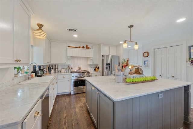 kitchen with sink, high end appliances, white cabinetry, a center island, and hanging light fixtures