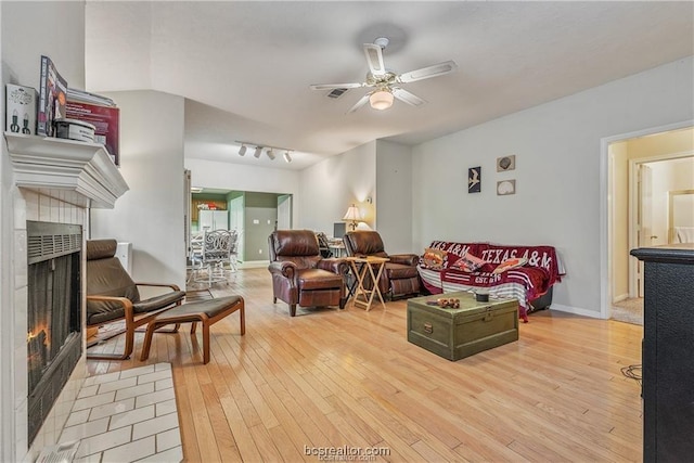 2308 Carnation Ct, College Station, TX 77840 - living area with a tiled fireplace, light wood finished floors, ceiling fan, and baseboards
