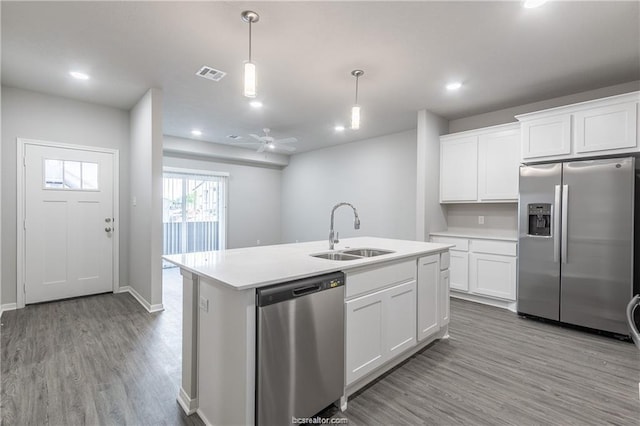 kitchen with stainless steel appliances, sink, white cabinets, ceiling fan, and an island with sink