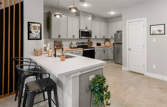 301 W 31st St Unit 103, Bryan, TX 77803 - kitchen featuring a kitchen breakfast bar, a peninsula, appliances with stainless steel finishes, light countertops, and decorative backsplash