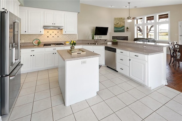 kitchen featuring a kitchen island, kitchen peninsula, white cabinetry, appliances with stainless steel finishes, and light tile patterned floors