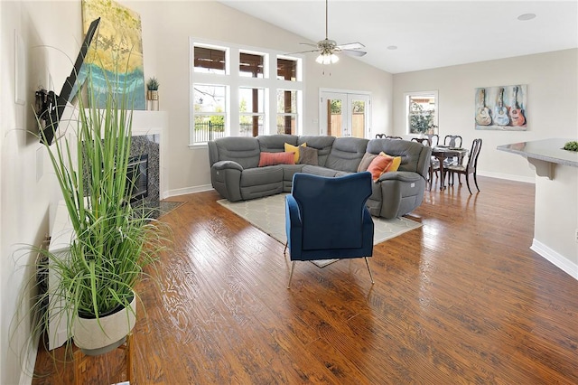 living room with ceiling fan, a high end fireplace, lofted ceiling, and wood-type flooring