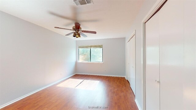 unfurnished bedroom with a closet, a ceiling fan, visible vents, wood finished floors, and baseboards