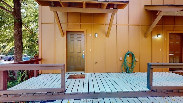 doorway to property featuring board and batten siding and a wooden deck