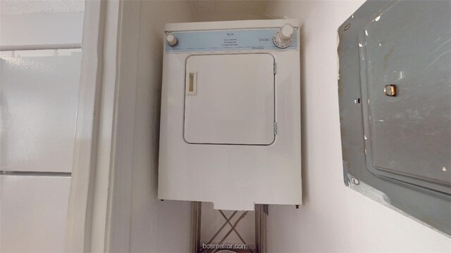 washroom with stacked washer and dryer, laundry area, and electric panel