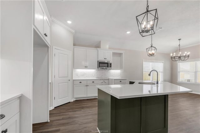 kitchen with white cabinets, a center island with sink, hanging light fixtures, and sink