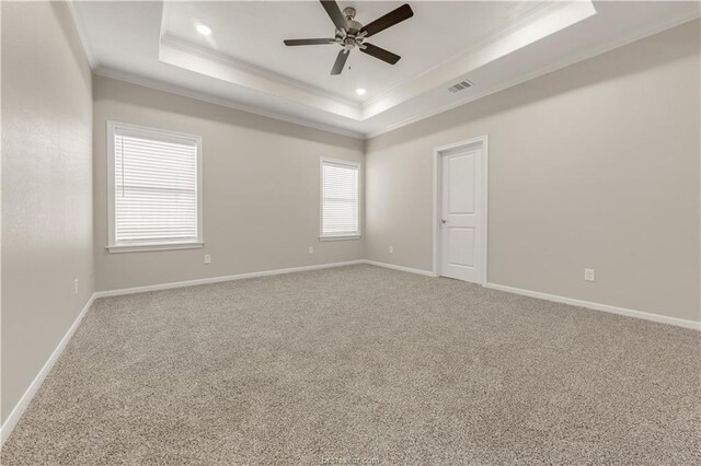 carpeted empty room featuring ceiling fan, ornamental molding, and a tray ceiling