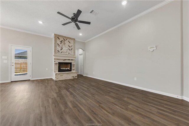 unfurnished living room with a fireplace, crown molding, ceiling fan, and dark wood-type flooring